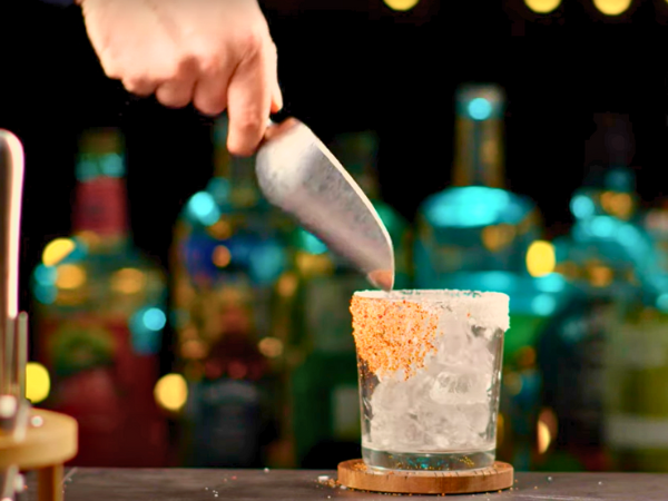 Take a cocktail shaker and fill it halfway with ice. This will help chill and properly mix the ingredients.