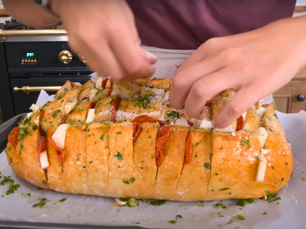 Next, stuff the shredded cheese into the cuts. Push the cheese down into the bread so it melts evenly during baking.